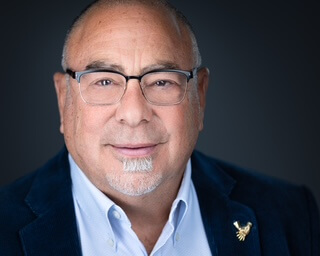 upper left white and gold international chiropractors logo. Photo of a man in a suit with glass, dr. neil cohen, white words on the right announcement, white and gold words underneath Welcoming Dr. Neil Cohen as Membership Ambassador